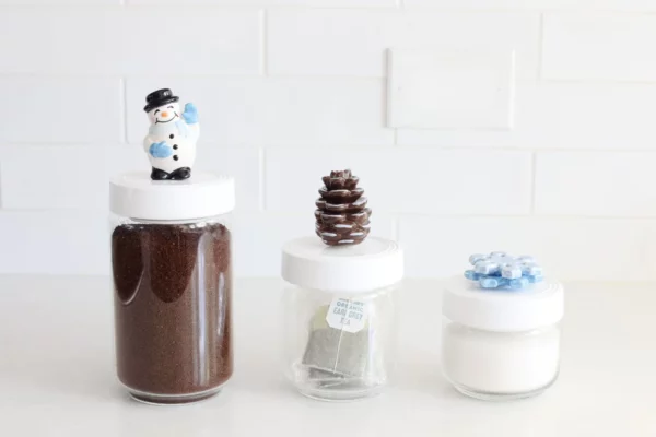 Nora Fleming Mini Frosty snowman and other minis attached to the lids of various sized canisters