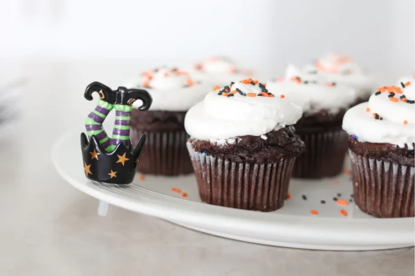 Nora Fleming Mini What's Up Witches attached to a tray of chocolate cupcakes