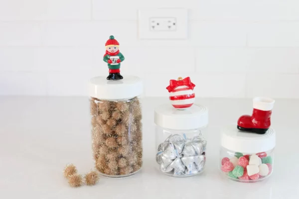 Nora Fleming Mini Fa la la Caroler and two other holiday minis attached to the lids of various sized canisters