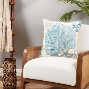throw pillow with a blue and golf sea fan motif pictured on an armchair